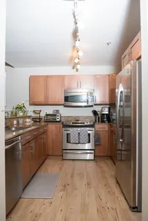 a kitchen with stainless steel appliances granite countertop a refrigerator a stove and a sink