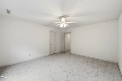 an empty room with chandelier fan and closet area