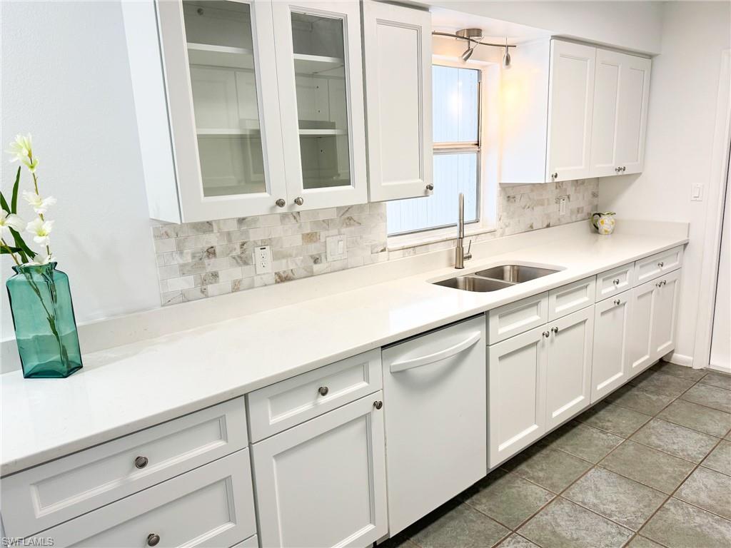 18584 Sebring Road Fort Myers, FL 33967 - Photo 6 of 25 Kitchen featuring sink, light tile patterned floors, dishwasher, white cabinetry, and backsplash