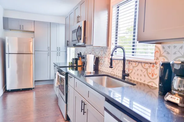 a kitchen with granite countertop a sink a refrigerator and a stove