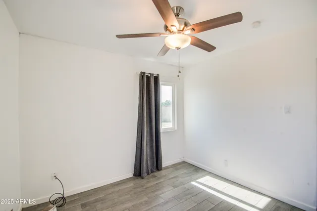 an empty room with a window and a ceiling fan