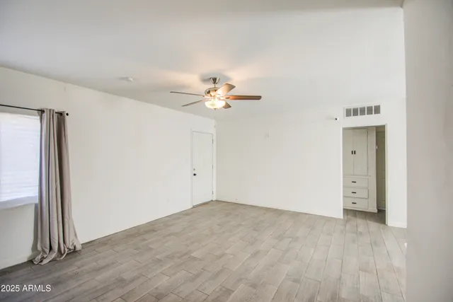 a view of a room with wooden floor and ceiling fan