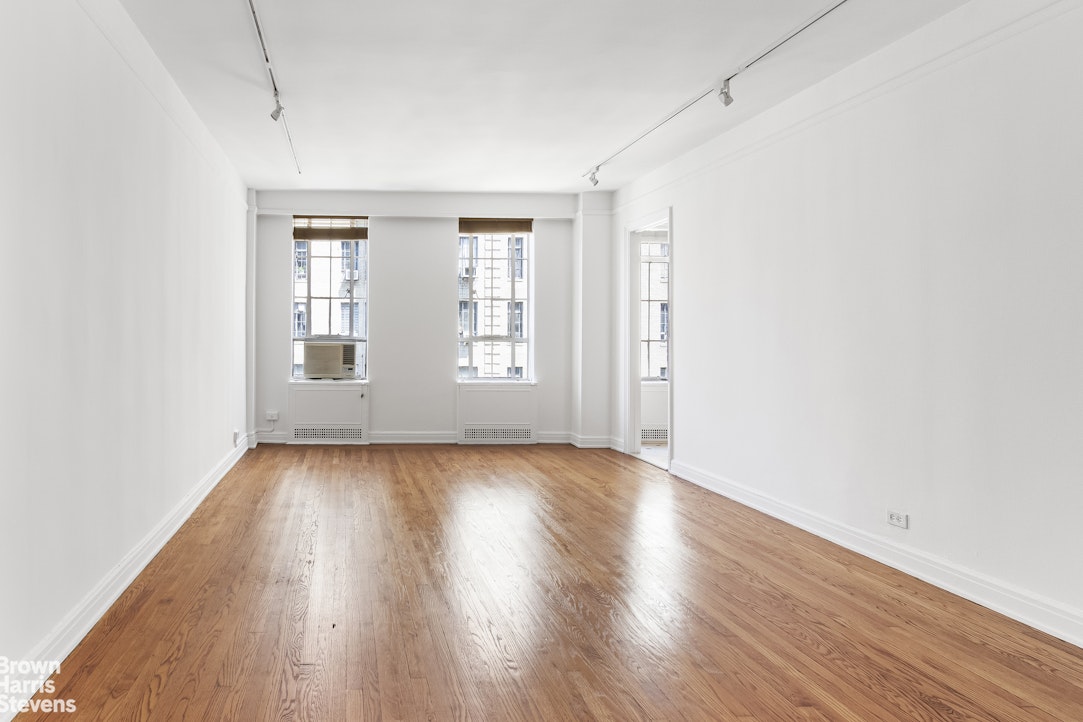 353 West 56th Street, Unit 9F Manhattan, NY 10019 - Photo 3 of 10 an empty room with wooden floor and windows