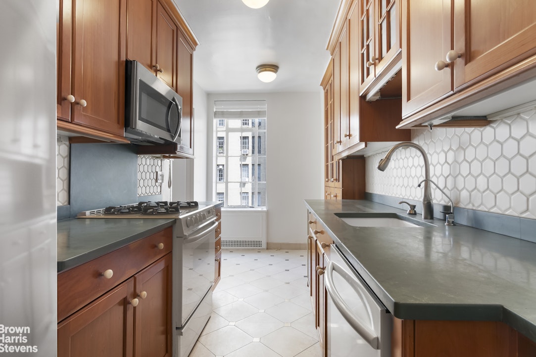 353 West 56th Street, Unit 9F Manhattan, NY 10019 - Photo 4 of 10 a kitchen with granite countertop a sink a stove and cabinets