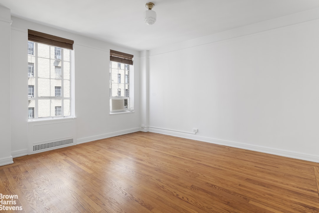 353 West 56th Street, Unit 9F Manhattan, NY 10019 - Photo 8 of 10 an empty room with wooden floor and windows