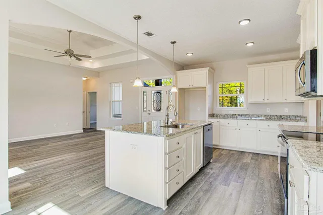a large white kitchen with a stove a sink dishwasher and a refrigerator with wooden floor