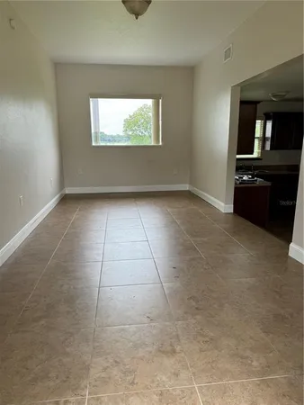 a view of an empty room and a kitchen