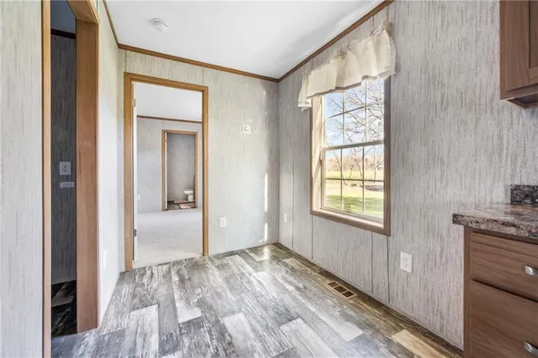 a view of a hallway with wooden floor and a bathroom