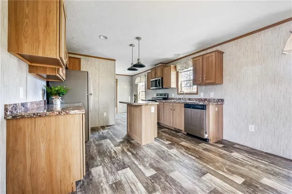 a kitchen with stainless steel appliances granite countertop a stove a sink dishwasher and a refrigerator with wooden floor