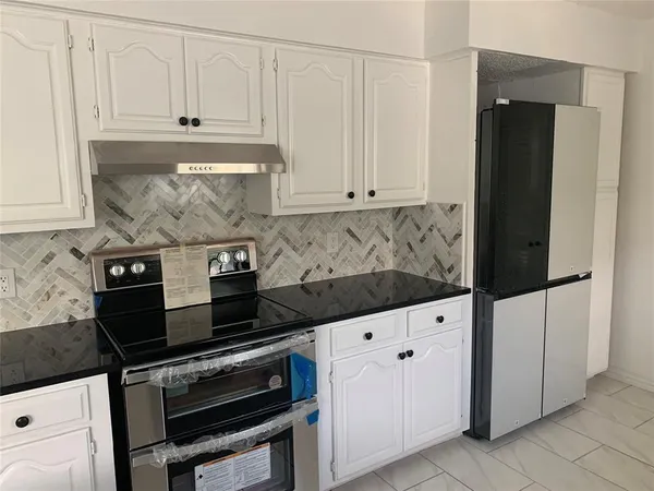 a kitchen with granite countertop white cabinets and black appliances
