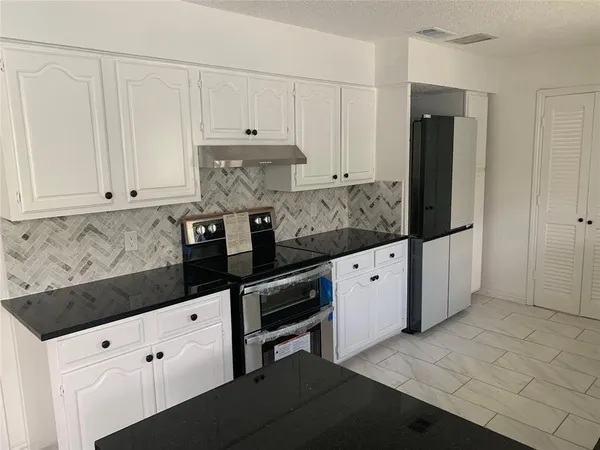 a kitchen with granite countertop white cabinets and stainless steel appliances