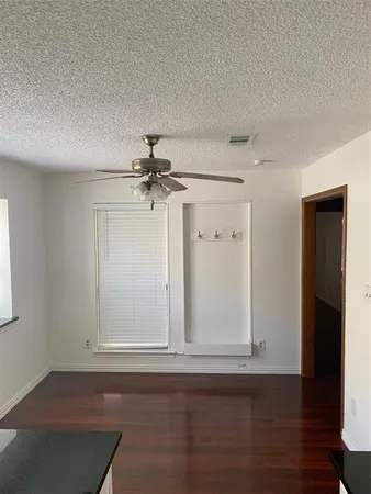 an empty room with wooden floor closet and windows