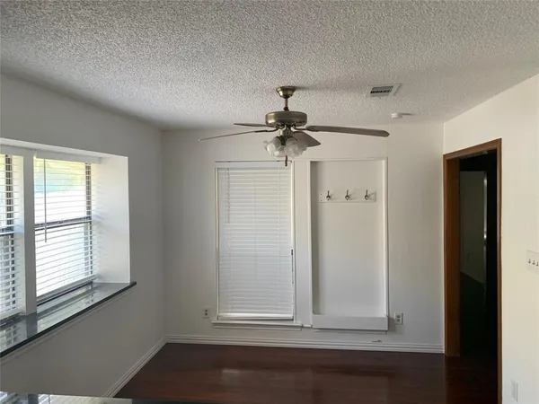 a view of empty room with wooden floor and fan