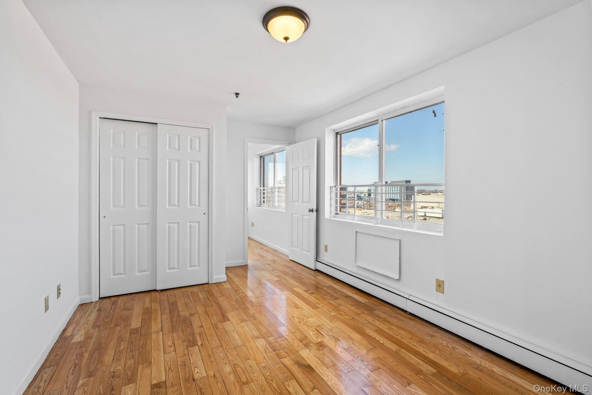 136-16 31st Road, Unit 8B Queens, NY 11354 - Photo 9 of 23 Unfurnished bedroom with a baseboard radiator, a closet, and light wood-type flooring