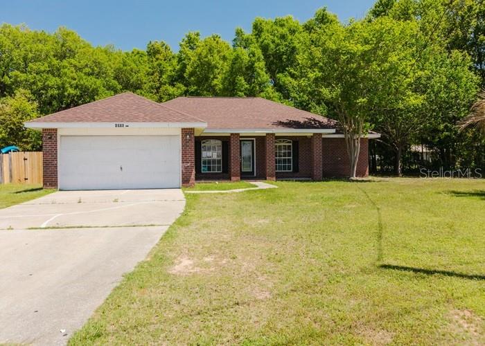 a front view of house with yard and trees in the background