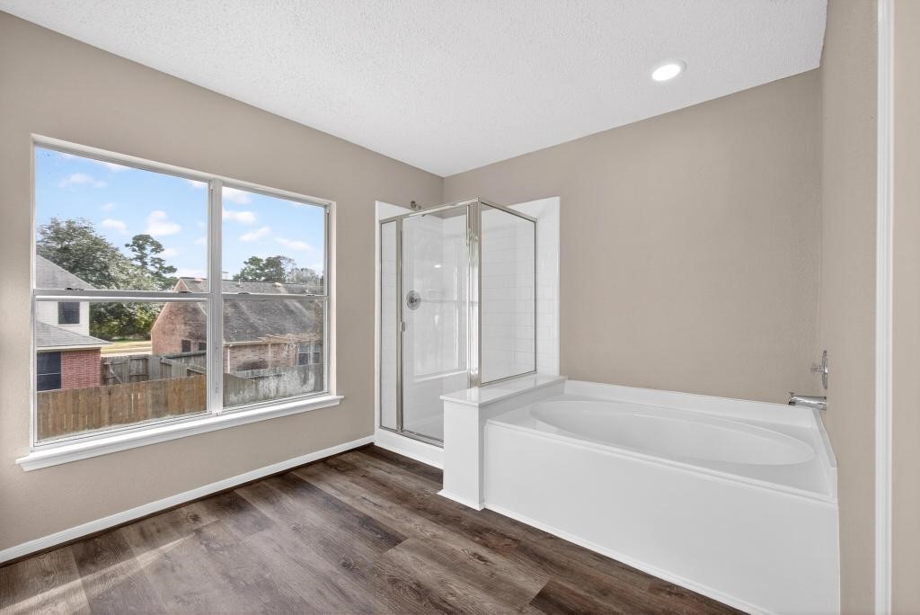 8815 Stoney Bend Drive Spring, TX 77379 - Photo 18 of 50 This bright bathroom features a large window, a spacious bathtub, and a separate glass-enclosed shower. The neutral tones and flooring add warmth and elegance.