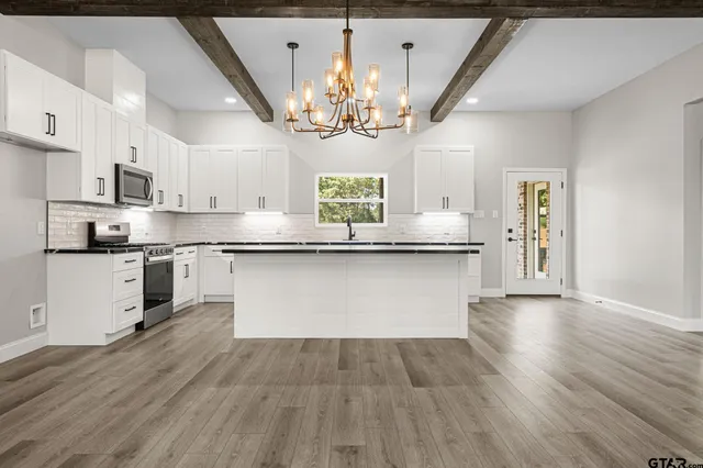 a large kitchen with stainless steel appliances granite countertop a sink dishwasher a stove a refrigerator and cabinets