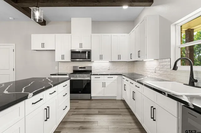 a white kitchen with granite countertop white cabinets and stainless steel appliances