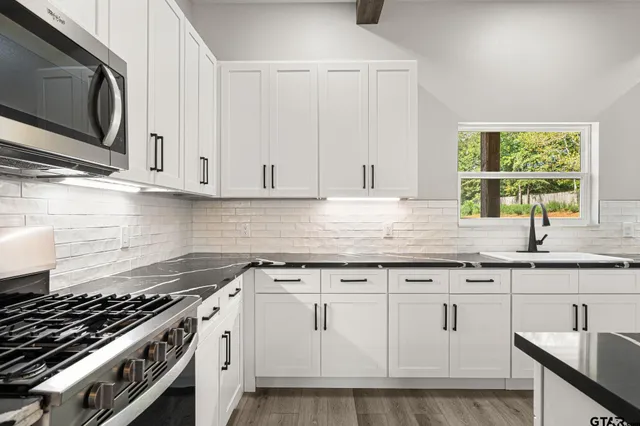 a kitchen with granite countertop white cabinets and appliances