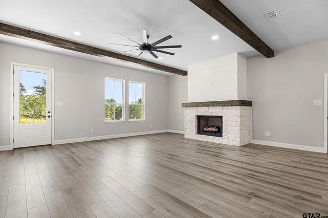 a view of an empty room with wooden floor fireplace and a window