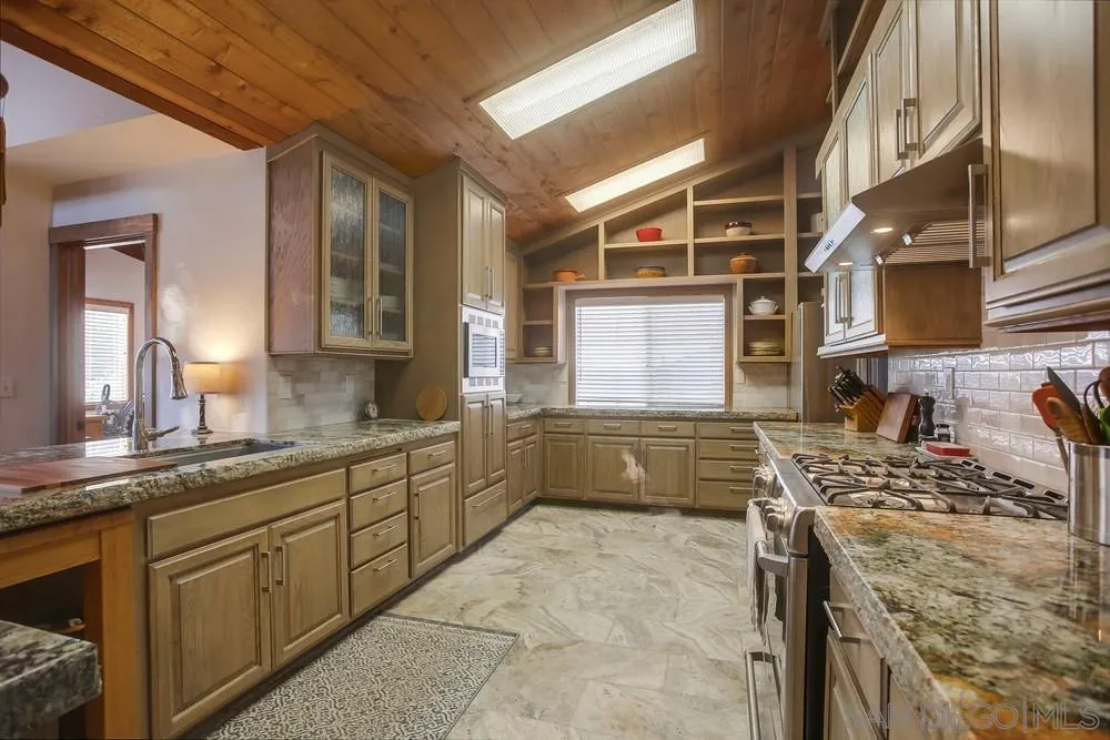 342 Cole Ranch Road Encinitas, CA 92024 - Photo 10 of 34 a kitchen with stainless steel appliances kitchen island granite countertop a sink and cabinets
