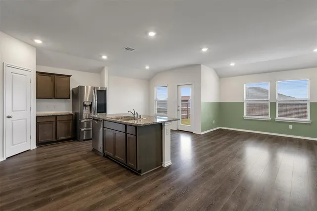 a kitchen with a sink wooden floor and stainless steel appliances