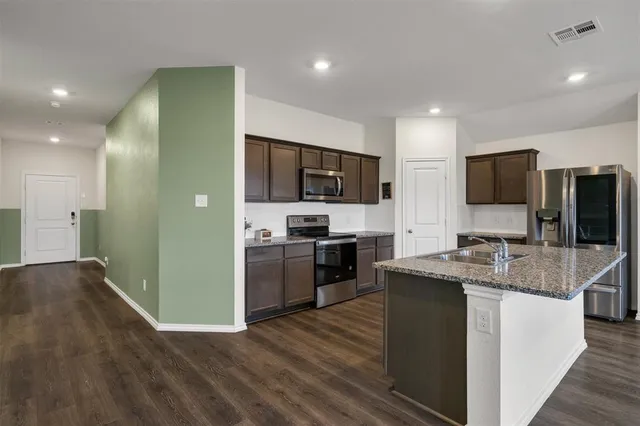 a kitchen with kitchen island granite countertop stainless steel appliances and a sink