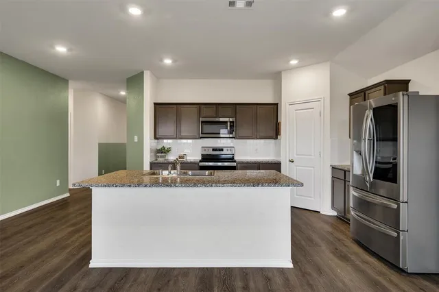 a kitchen with stainless steel appliances granite countertop a sink a stove a refrigerator and a microwave