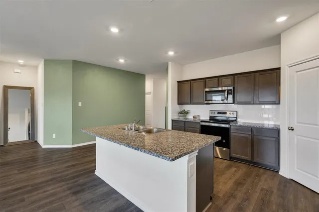 a kitchen with kitchen island granite countertop stainless steel appliances and wooden cabinets