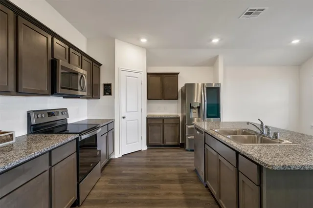 a kitchen with stainless steel appliances granite countertop a sink stove microwave and refrigerator