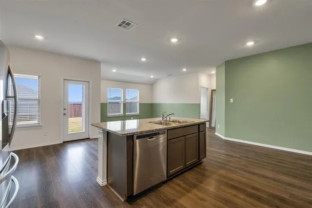 a kitchen with stainless steel appliances granite countertop a sink and wooden floor
