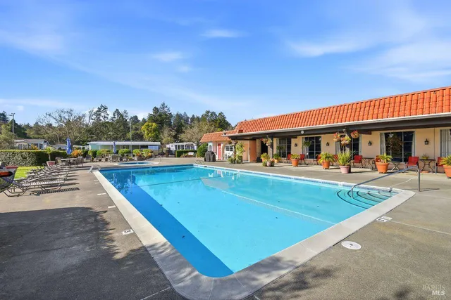 a view of swimming pool with outdoor seating and trees in the background