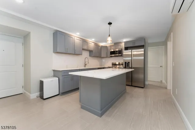 a kitchen with kitchen island cabinets a sink a counter and a refrigerator