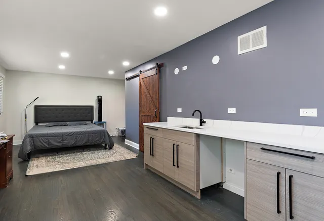 a living room with stainless steel appliances kitchen island a sink dishwasher a stove and a refrigerator with wooden floor