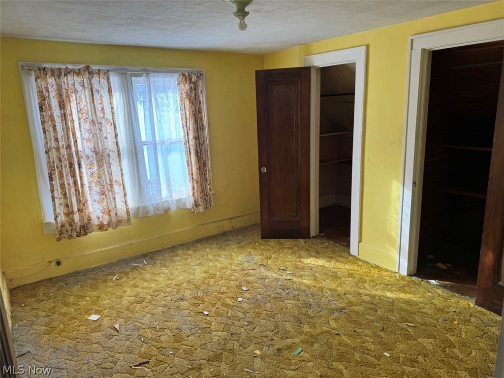 586 Brittain Road Akron, OH 44305 - Photo 10 of 19 Unfurnished bedroom featuring a closet, a textured ceiling, and a spacious closet