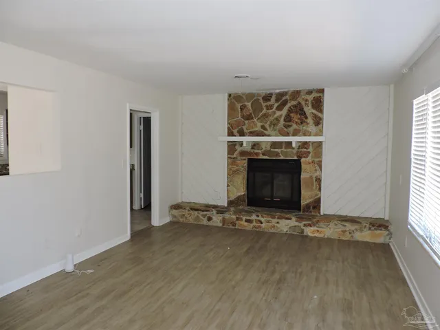 an empty room with windows and fireplace