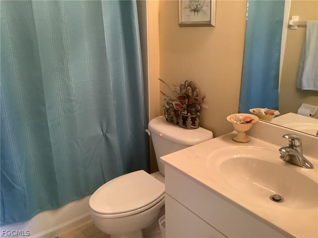 4791 Fairloop Run Lehigh Acres, FL 33973 - Photo 15 of 19 a bathroom with a sink a toilet and shower curtain