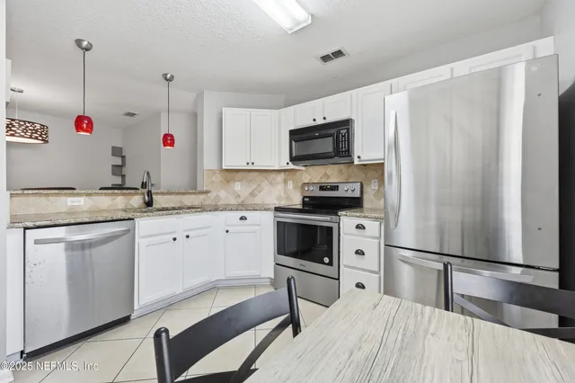 a kitchen with white cabinets stainless steel appliances and sink
