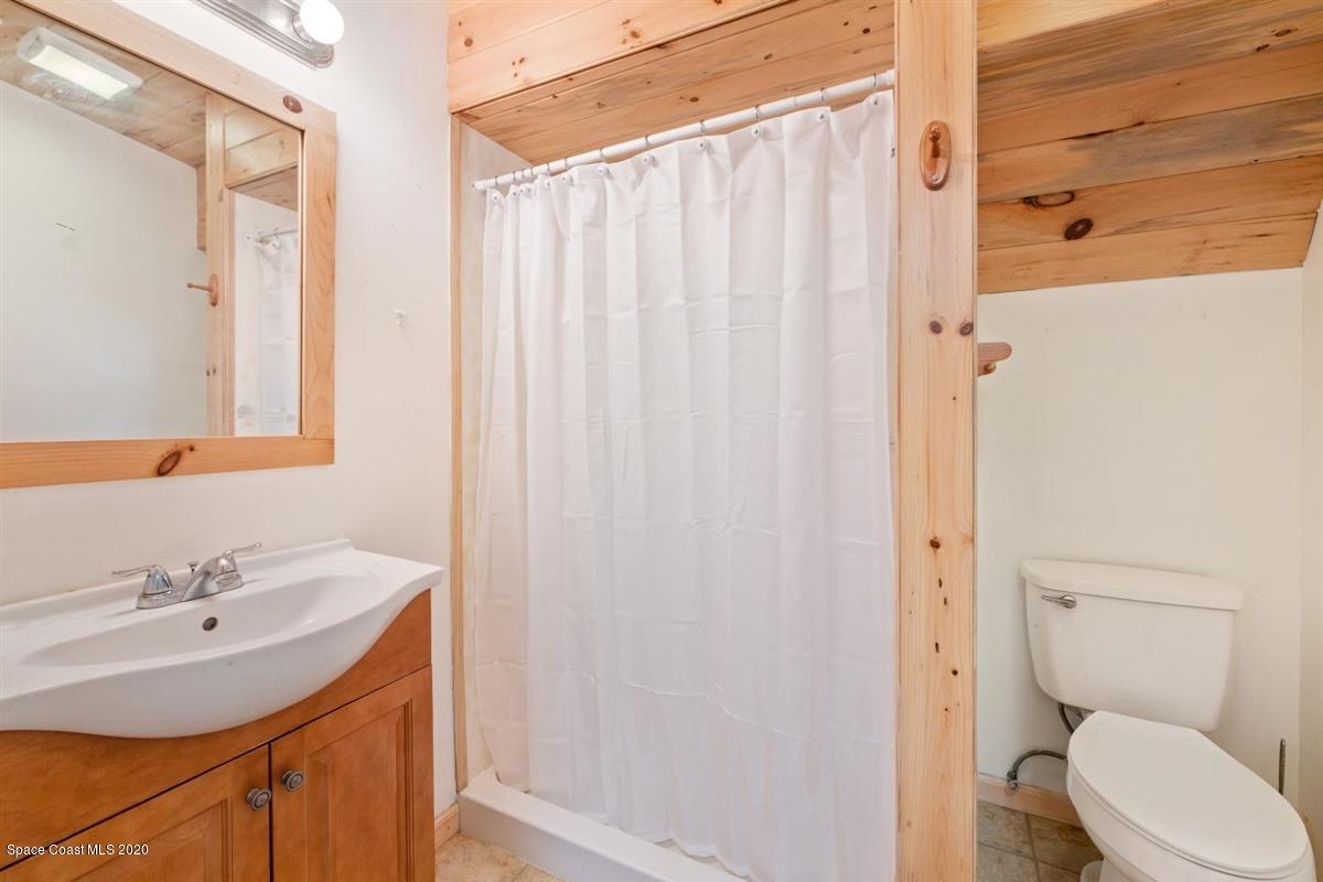3600 Leghorn Road Grant Valkaria, FL 32950 - Photo 26 of 33 a bathroom with a sink a toilet and shower curtain