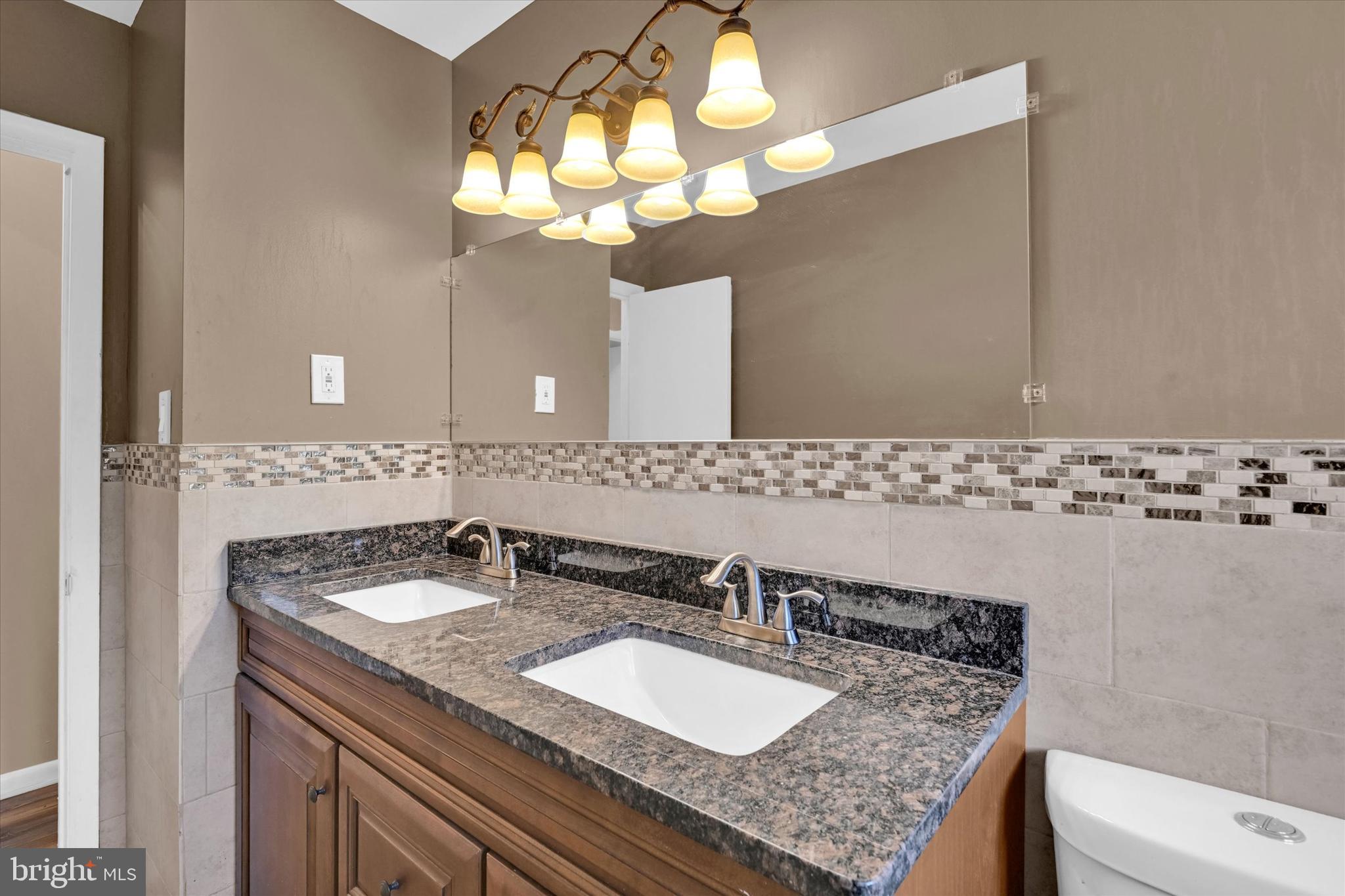 6812 Pepper Street Capitol Heights, MD 20743 - Photo 16 of 42 a bathroom with a granite countertop sink a toilet and a mirror