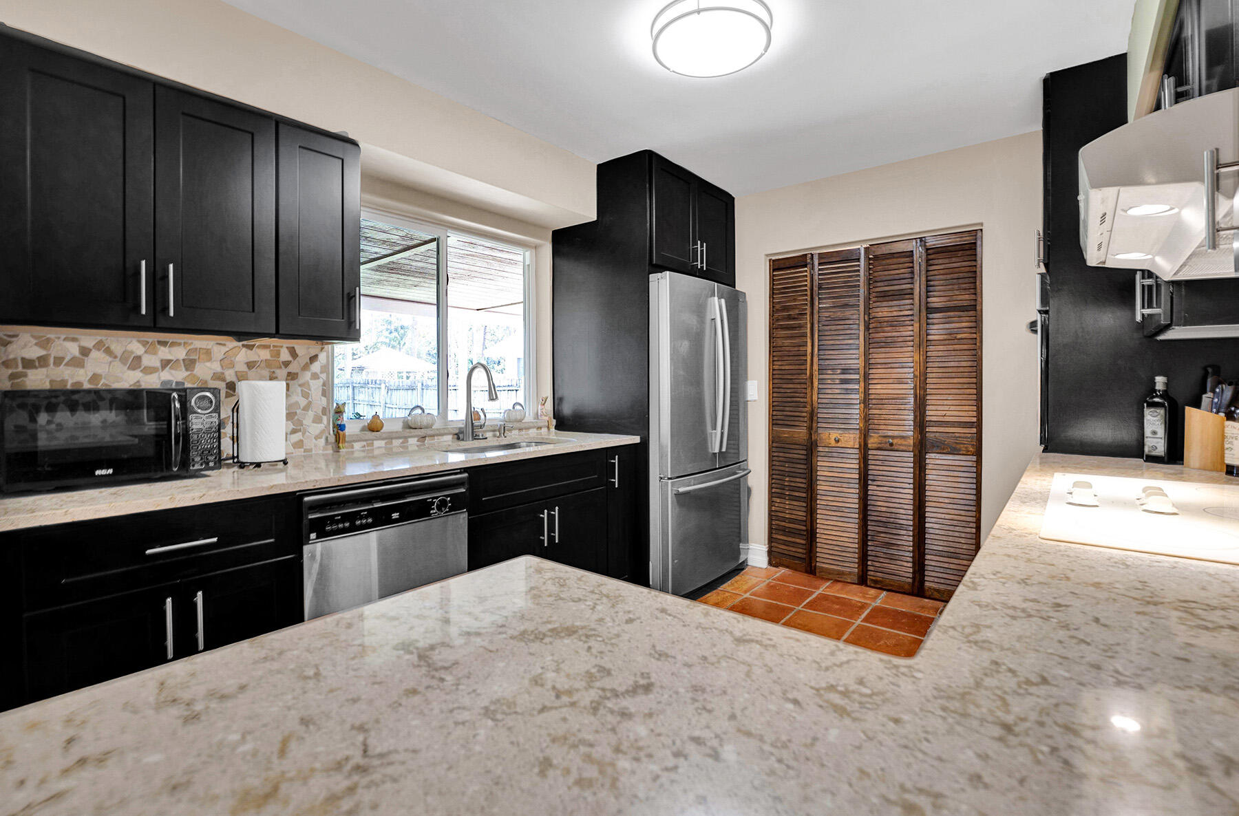 5385 Adams Road Delray Beach, FL 33484 - Photo 9 of 46 a kitchen with stainless steel appliances kitchen island granite countertop a refrigerator stove and sink