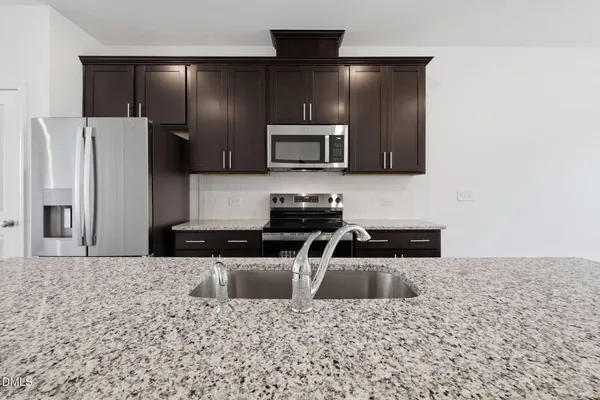 a kitchen with granite countertop a refrigerator and a stove top oven