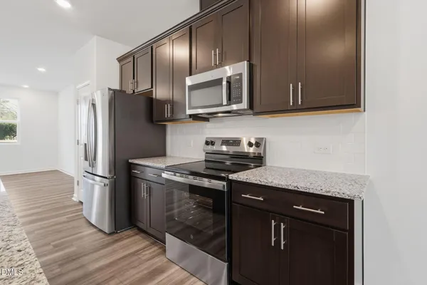 a kitchen with stainless steel appliances granite countertop a stove a refrigerator and a microwave