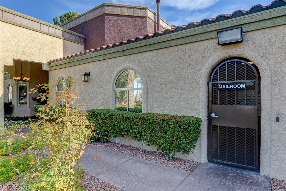7885 West Flamingo Road, Unit 1050 Las Vegas, NV 89147 - Photo 59 of 62 A terracotta-tiled roofline crowns this building's stucco facade, featuring an arched window and a wrought-iron mailroom entrance.