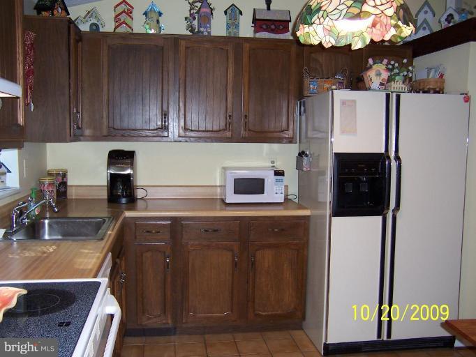 9417 Gunview Road Nottingham, MD 21236 - Photo 9 of 30 a kitchen with stainless steel appliances granite countertop a refrigerator a sink dishwasher and cabinets with wooden floor