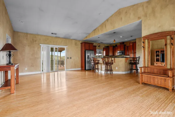 a view of a living room kitchen with stainless steel appliances wooden floor dining table and chair