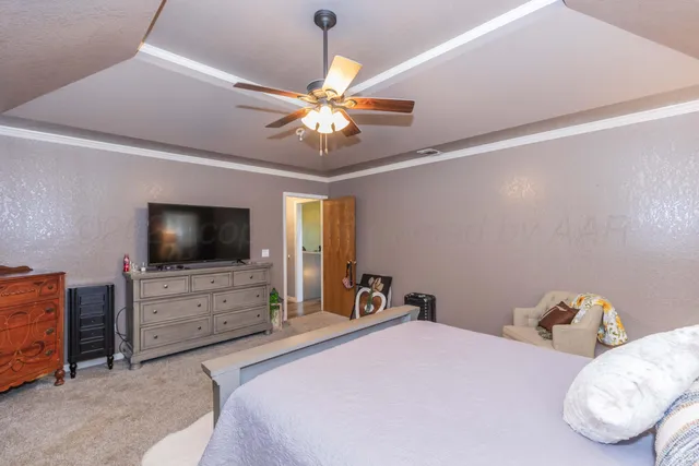a bedroom with a bed and a flat tv screen on dresser