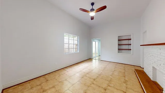 an empty room with windows and ceiling fan