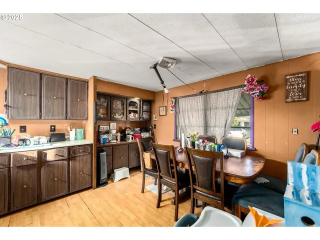 a kitchen with stainless steel appliances kitchen island granite countertop a table chairs in it and wooden floors