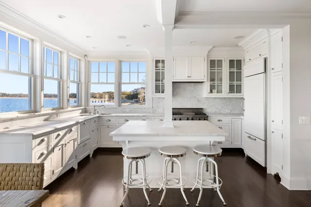 a large white kitchen with stainless steel appliances kitchen island granite countertop a stove a sink and white cabinets